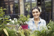 Retrato sorrindo jovem jardinagem com plantas em vaso no pátio — Fotografia de Stock