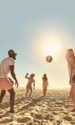 Молоді друзі грають з пляжним м'ячем на сонячному літньому пляжі — стокове фото