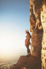 Female rock climber looking at sunny ocean view — Stock Photo