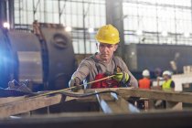 Male worker with tape measure measuring steel in factory — Stock Photo