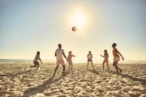 Молоді друзі грають з пляжним м'ячем на сонячному літньому пляжі — стокове фото