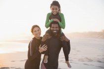 Retrato sorridente, família feliz em ternos molhados na praia ensolarada de verão — Fotografia de Stock