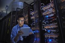 Fokussierter männlicher IT-Techniker mit digitalem Tablet im dunklen Serverraum — Stockfoto