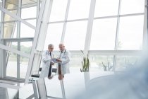 Male doctors with clipboard talking in hospital lobby — Stock Photo