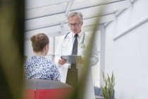 Arzt mit Klemmbrett im Gespräch mit Patientin in Krankenhauslobby — Stockfoto