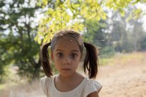 Portrait wide-eyed girl with pigtails in yard — Stock Photo