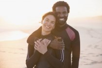 Retrato sorridente, casal afetuoso abraçando na praia de verão por do sol — Fotografia de Stock