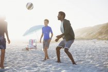 Pai e crianças jogando futebol na praia ensolarada de verão — Fotografia de Stock