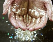 Hands cupping gold glitter — Stock Photo