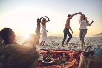 Jovens casais dançando, curtindo piquenique na praia de verão — Fotografia de Stock