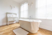 Blanco, lujoso cuarto de baño interior escaparate casa con bañera de remojo y parquet piso de madera - foto de stock