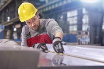 Focused male worker examining steel in factory — Stock Photo