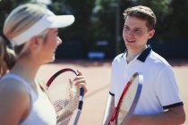 Male and female tennis players talking, holding tennis rackets — Stock Photo