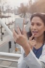 Mujer revisando maquillaje con teléfono de cámara en puente urbano, Londres, Reino Unido - foto de stock