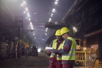 Steelworkers with clipboard meeting in steel mill — Stock Photo