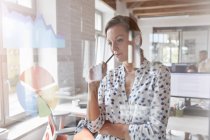 Nachdenkliche Geschäftsfrau überprüft Schaubild und Tortendiagramm am Fenster im Büro — Stockfoto