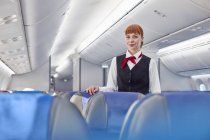 Porträt selbstbewusste Flugbegleiterin im Flugzeug — Stockfoto