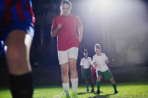Jeunes joueuses de soccer pratiquant des exercices sportifs d'agilité sur le terrain la nuit — Photo de stock