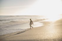 Mulher silhueta andando na ensolarada praia do oceano de verão — Fotografia de Stock