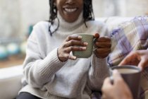 Women talking and drinking tea on sofa — Stock Photo