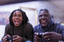 Захоплений дідусь і онук грають у відеогру — стокове фото