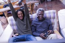 Entusiástico avô e neto jogando videogame no sofá — Fotografia de Stock