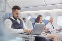 Бизнесмен, работающий за ноутбуком на самолете — стоковое фото