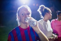 Jovem jogadora de futebol bebendo de garrafa de água — Fotografia de Stock