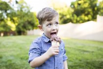 Menino pré-escolar comendo sorvete cone no quintal de verão — Fotografia de Stock