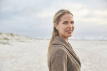 Porträt lächelnde blonde Frau am Winterstrand — Stockfoto