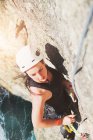 Escala de escalada de roca femenina determinada y enfocada - foto de stock