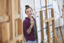 Female artist painting at easel in art class studio — Stock Photo