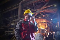 Steelworker talking, using walkie-talkie in steel mill — Stock Photo