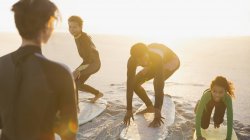 Pai surfista ensinar as crianças a surfar em pranchas de surf na praia ensolarada verão — Fotografia de Stock