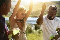 Playful young friends dancing at sunny summer riverside — Stock Photo