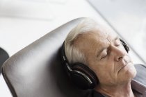 Senior mit Kopfhörer hört Musik und liegt — Stockfoto