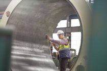 Чоловік-інженер вивчає великий сталевий циліндр на заводі — стокове фото