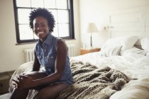 Portrait smiling, confident woman sitting on bed — Stock Photo