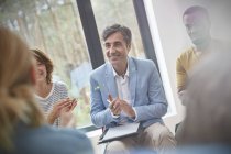 Smiling man clapping in group therapy session — Stock Photo