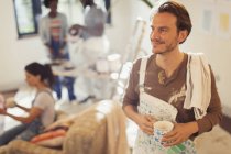 Smiling man painting, taking coffee break — Stock Photo