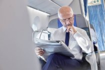 Geschäftsmann liest Zeitung im Flugzeug — Stockfoto