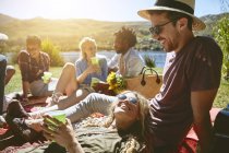 Молодые друзья отдыхают, наслаждаются пикником на солнечном берегу — стоковое фото