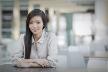 Portrait confident businesswoman at table at modern office — Stock Photo