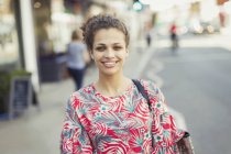 Портрет усміхненої молодої жінки на міській вулиці — стокове фото