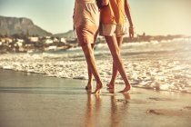 Barfuß spazieren junge Frauen am sonnigen Sommerstrand am Meer — Stockfoto