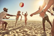 Jovens amigos brincalhões brincando com bola de praia na praia ensolarada de verão — Fotografia de Stock
