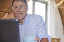 Hombre mayor beber café y el uso de ordenador portátil - foto de stock