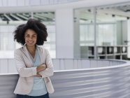 Portrait smiling confident businesswoman with arms crossed in office atrium — Stock Photo