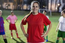 Portrait confident, smiling young female soccer player on field at night — Stock Photo