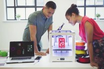Diseñadores viendo impresora 3D en la mesa - foto de stock